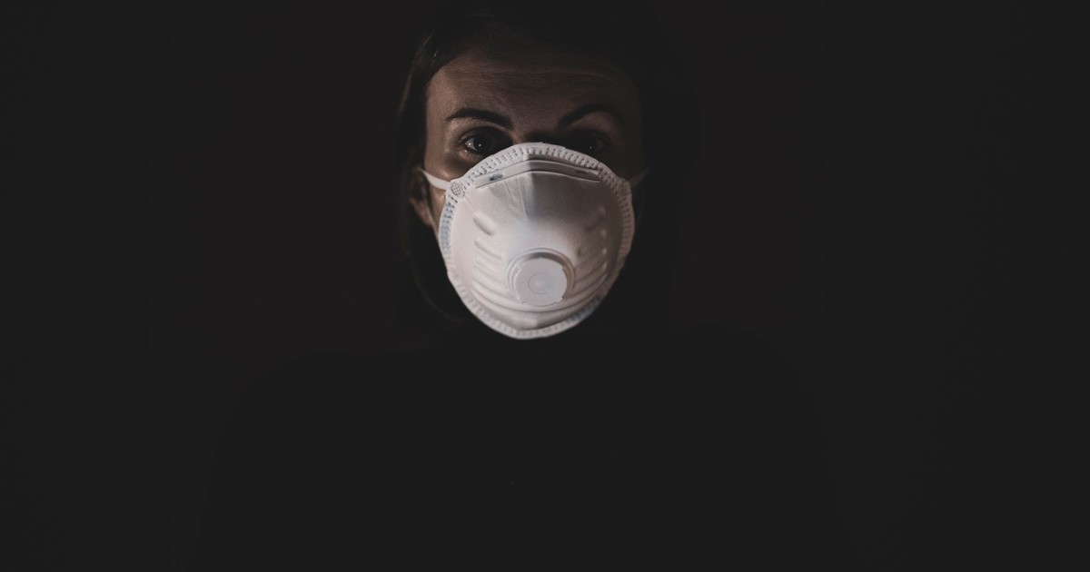 A person wearing an N95 mask in a dimly lit environment, emphasizing safety during the pandemic.