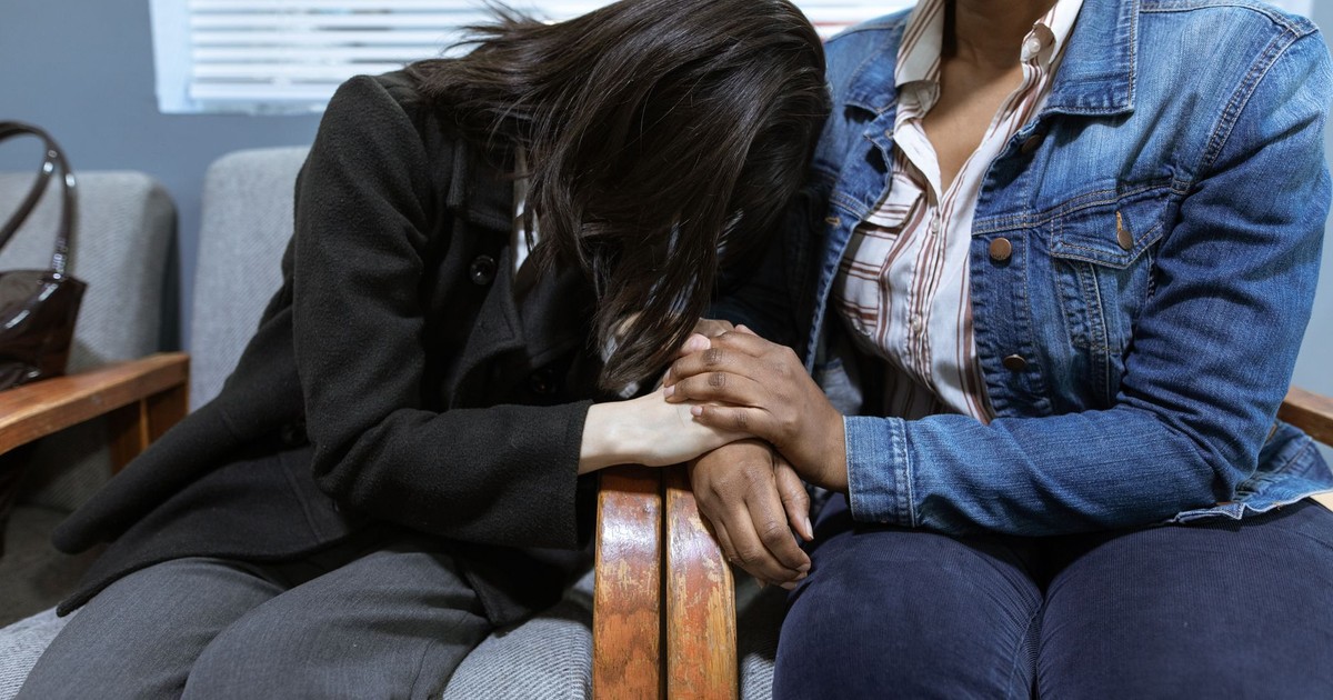 Two women offering emotional support, demonstrating compassion in a hospital setting.