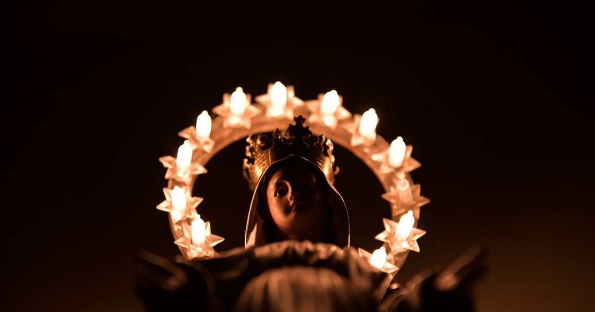 A low angle shot of an illuminated Madonna statue, symbolizing sacred belief, in Verona, Italy.