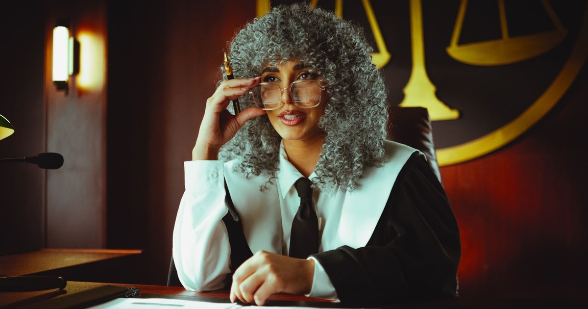 An elegant judge in robes sits at a desk in a courtroom, poised and authoritative.