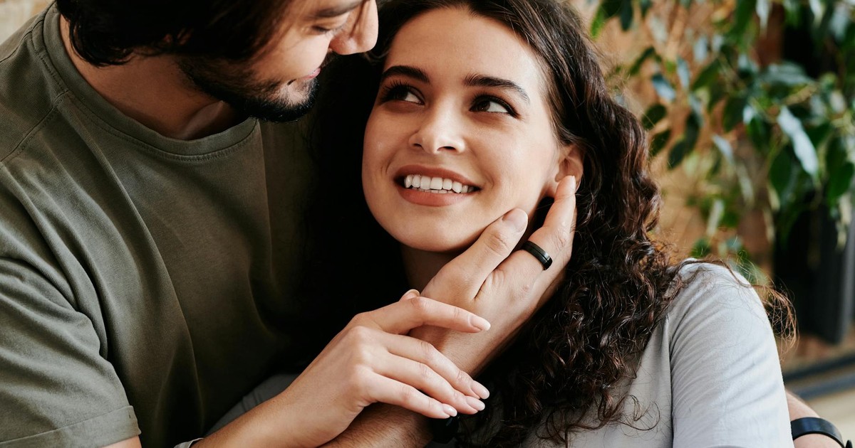 Loving couple embracing in a warm, cozy indoor setting with greenery, symbolizing affection and connection.