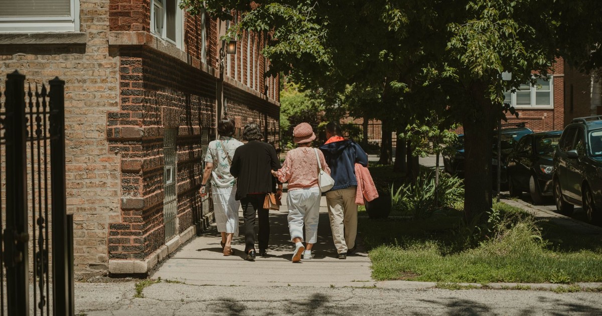 A diverse group of women walking together on a sunny day in a Chicago neighborhood street.