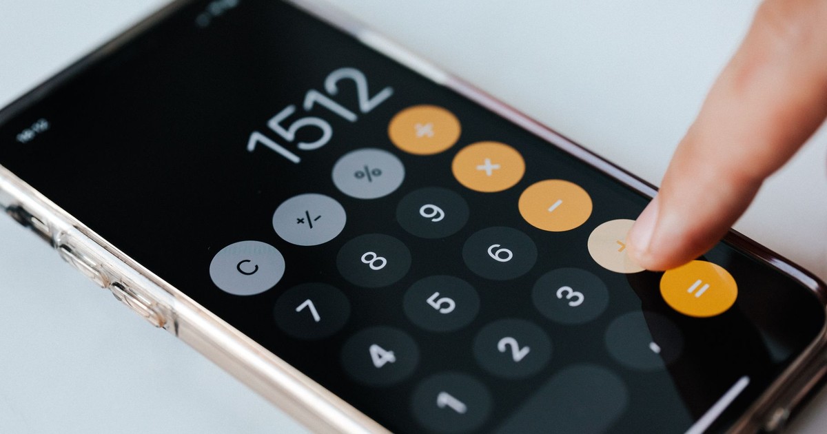 From above of crop faceless financier touching plus sign on screen of cellphone while using calculator application and calculating total amount