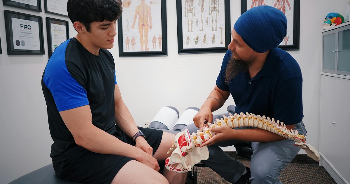 A doctor explains spinal issues to a patient using a spine model during a medical consultation.