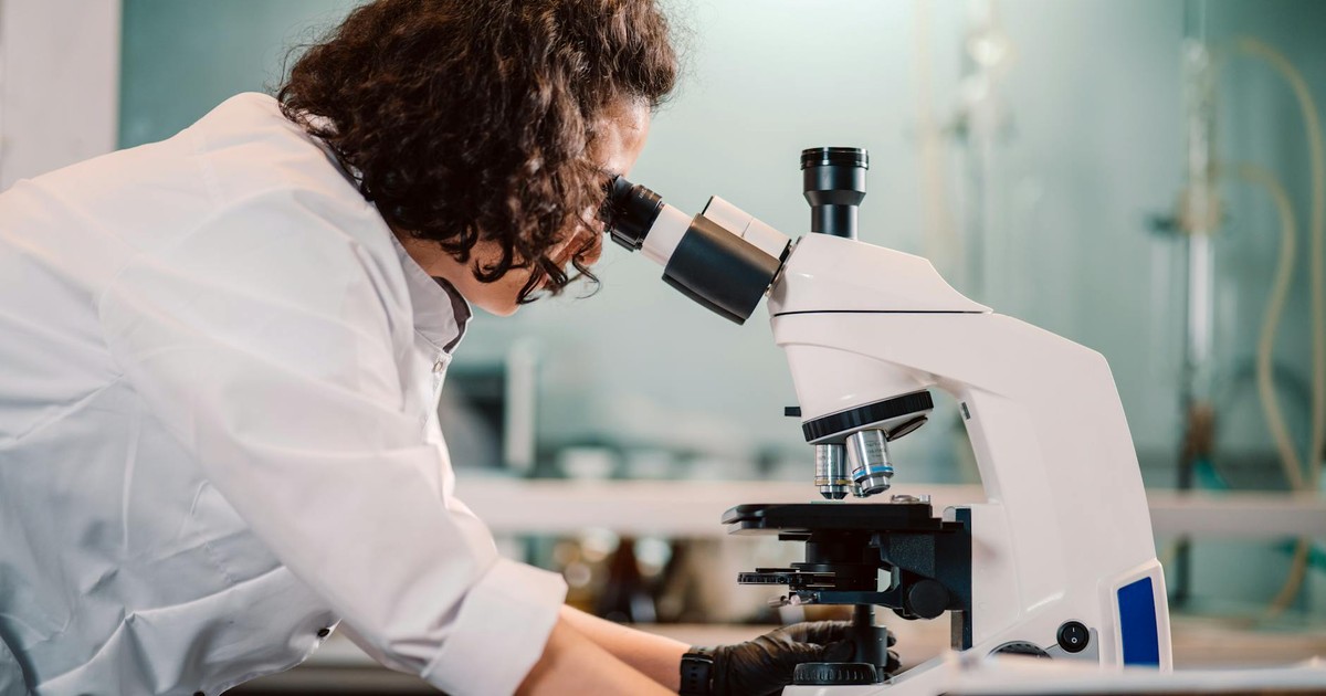 A woman scientist using a microscope in a laboratory setting.