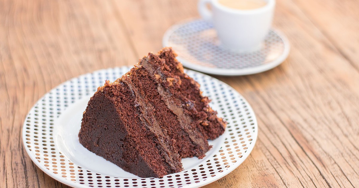 Delicious slice of chocolate cake served with coffee on a rustic wooden table, perfect for dessert lovers.