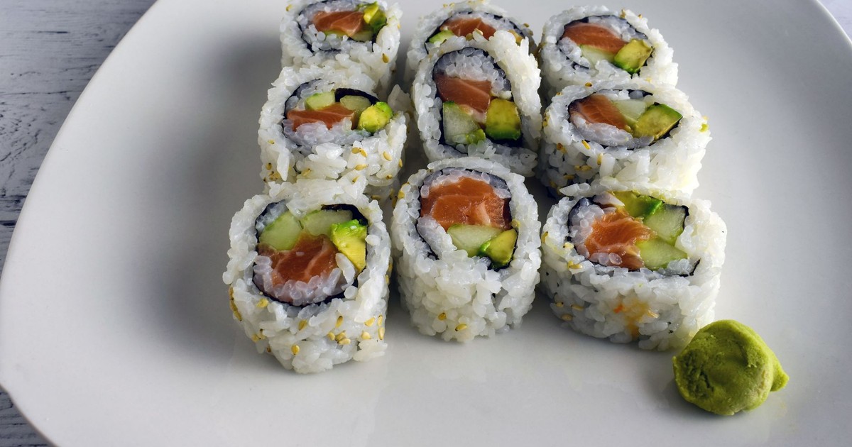 Delicious salmon and avocado sushi rolls neatly plated with a dollop of wasabi, a Japanese culinary delight.