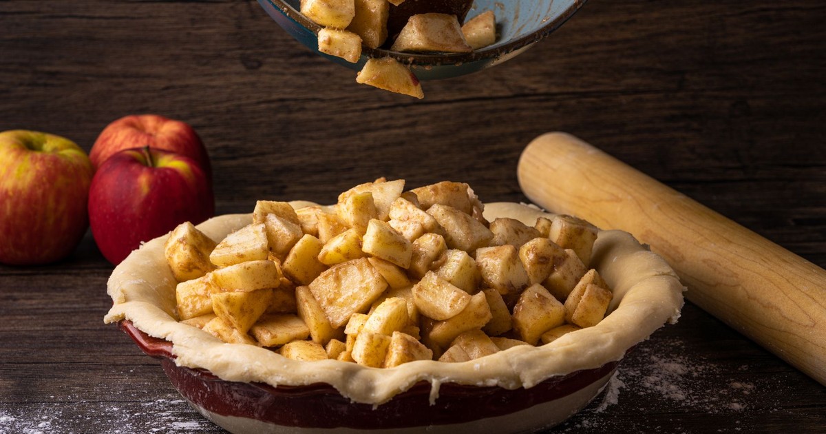Fresh apple pie preparation with cinnamon-spiced apples in a dough crust, ready for baking.