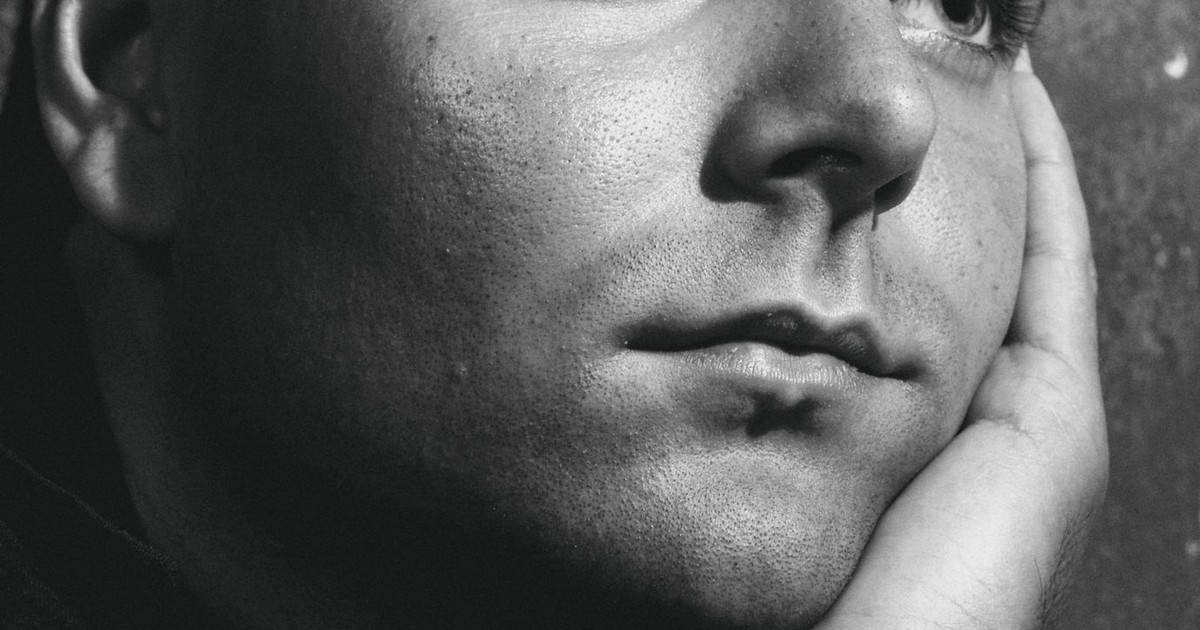 A close-up black and white portrait of a man in deep thought, with his hand on his chin.