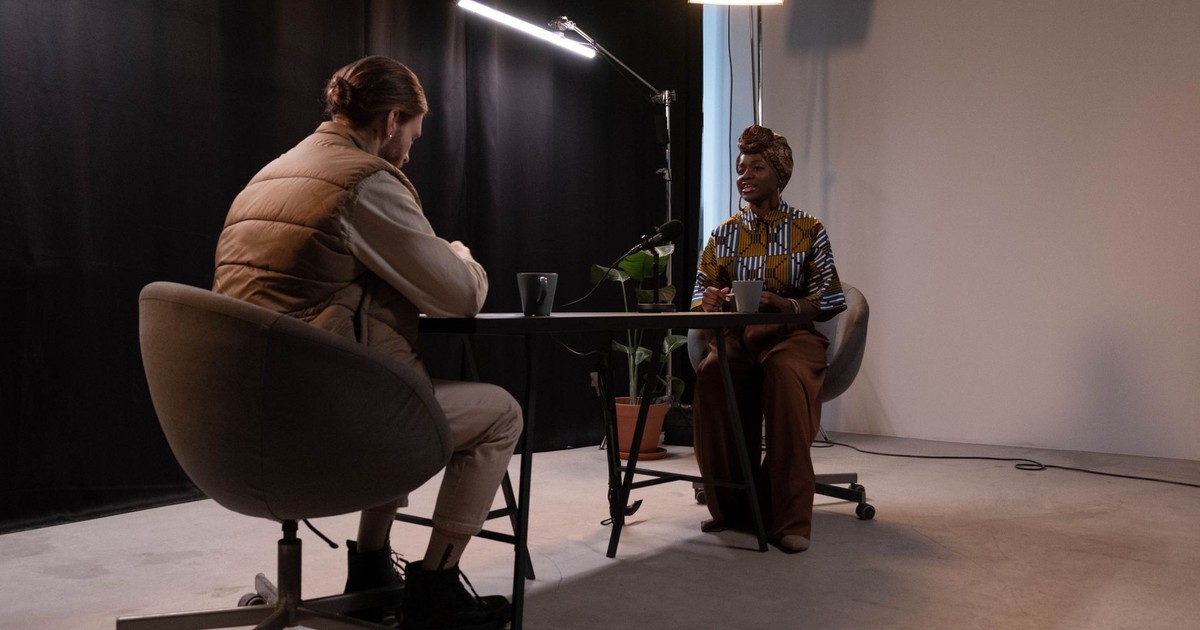 A man and woman recording a podcast in a professional studio environment.