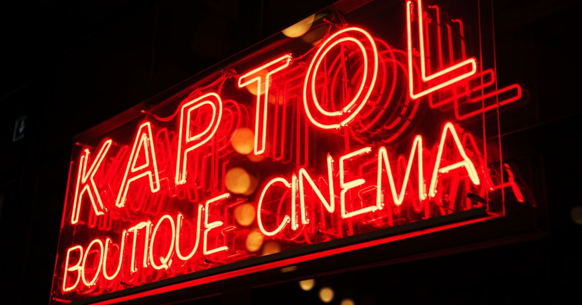 Vibrant neon sign of Kaptol Boutique Cinema glowing at night, creating a retro ambiance.