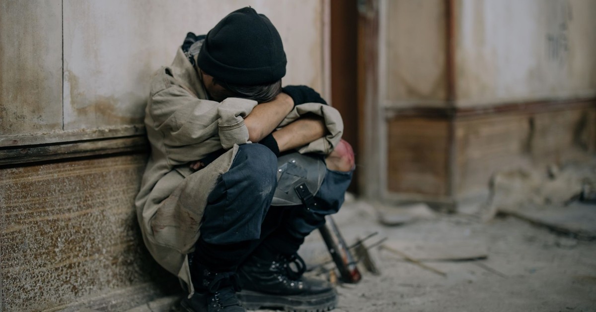 A young boy sits alone, appearing sad and forlorn, in an abandoned building setting.