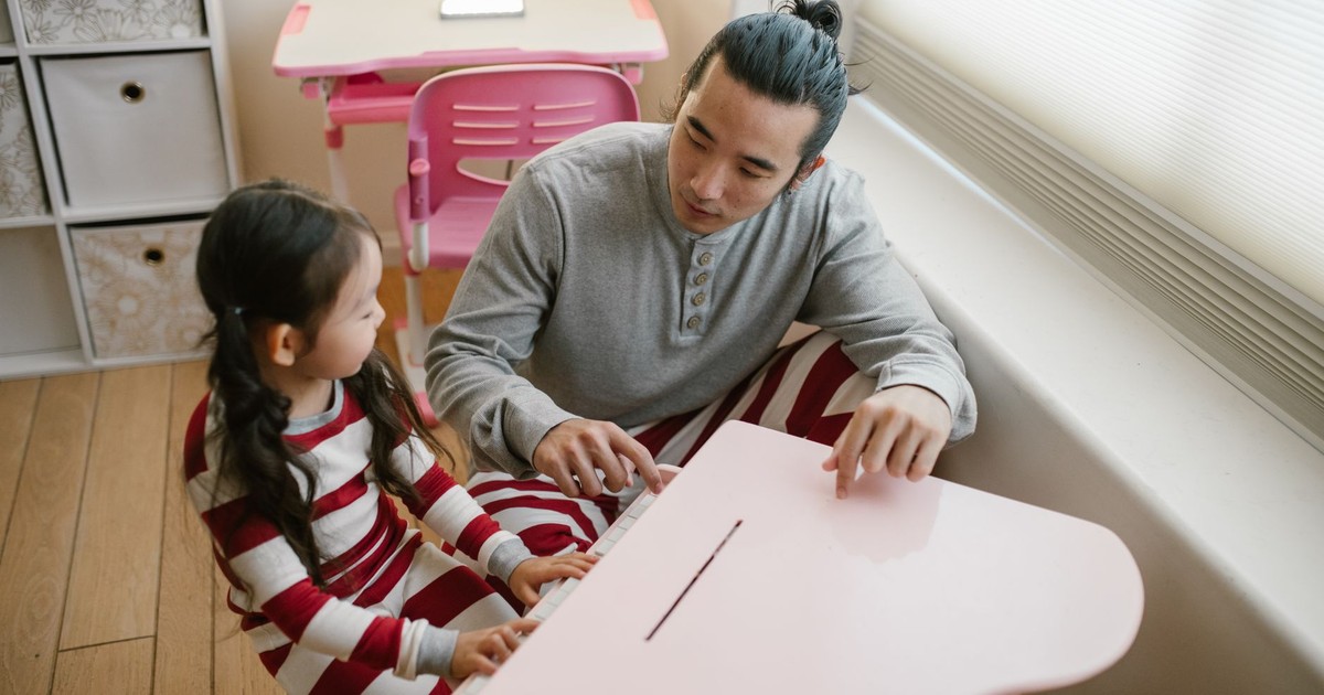 A father and daughter playing piano together in a cozy home setting, enhancing family bonding.