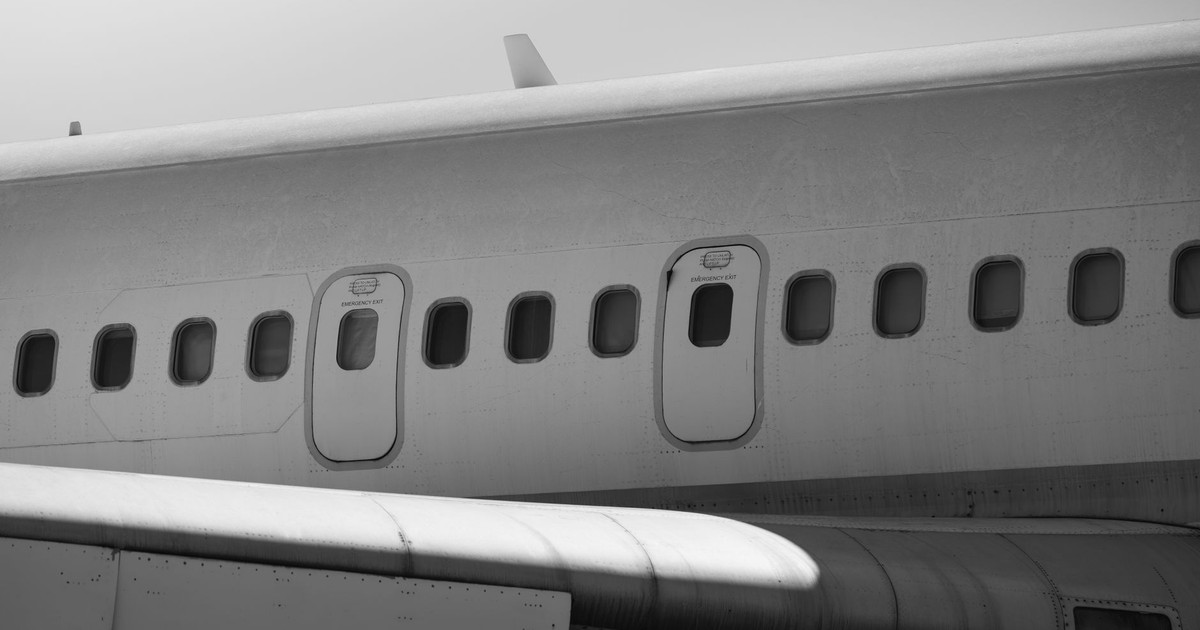Detailed black and white photo of airplane exterior showing fuselage and windows, emphasizing textures.