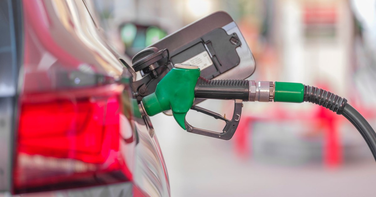 A close-up view of a fuel pump nozzle inserted into a car's tank at a gas station.