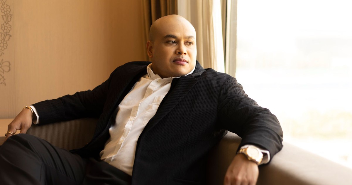 Confident businessman sitting indoors, gazing outside with a thoughtful expression.