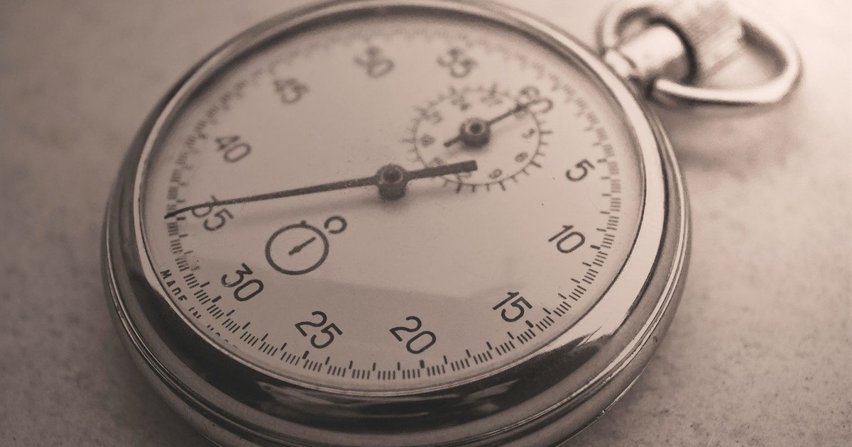 An antique silver pocket watch captured in a sepia tone, showcasing intricate details.