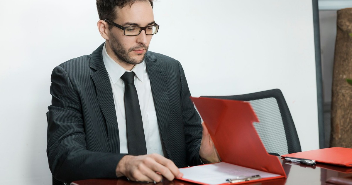 Professional man in suit reviewing papers at office desk with focus and determination.