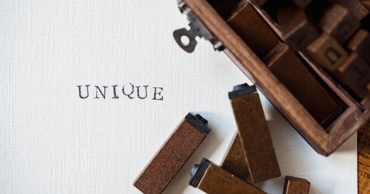 Wooden blocks spelling 'UNIQUE' stamped on textured white canvas