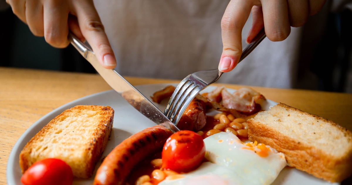 Close-up of a traditional English breakfast with sausage, eggs, beans, and toast.