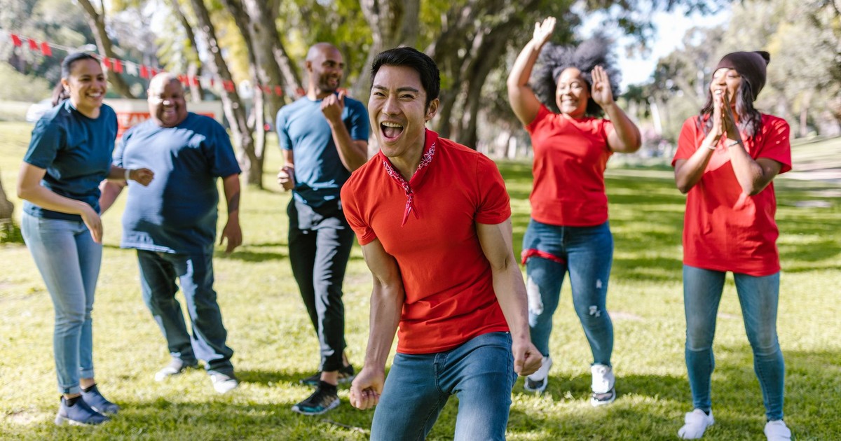 Group of happy adults playing and bonding in a park during a fun team building event.