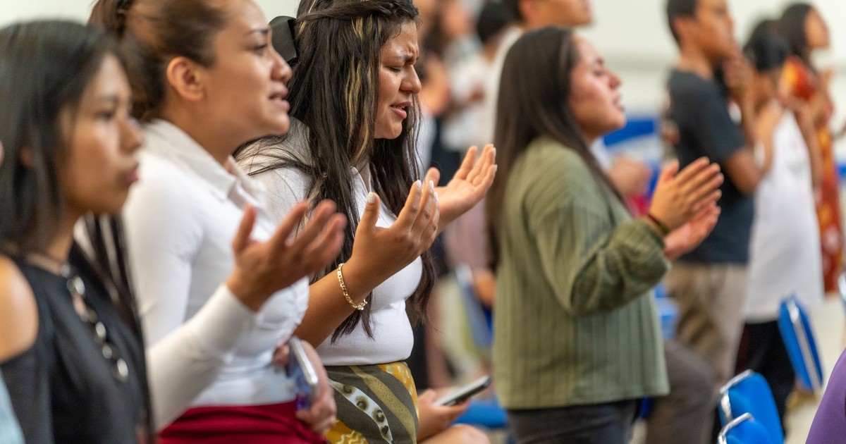 Young Hispanic women engaged in prayer inside a Ciudad de México church.