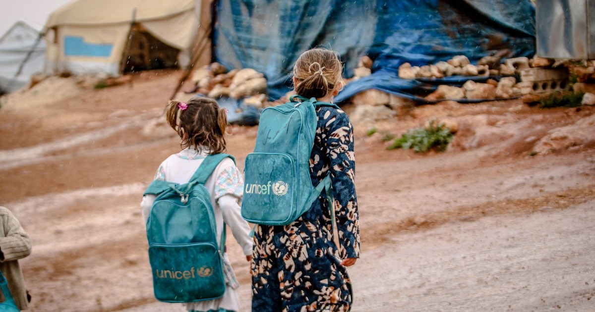 Children at a refugee camp in Syria carrying blue UNICEF backpacks.