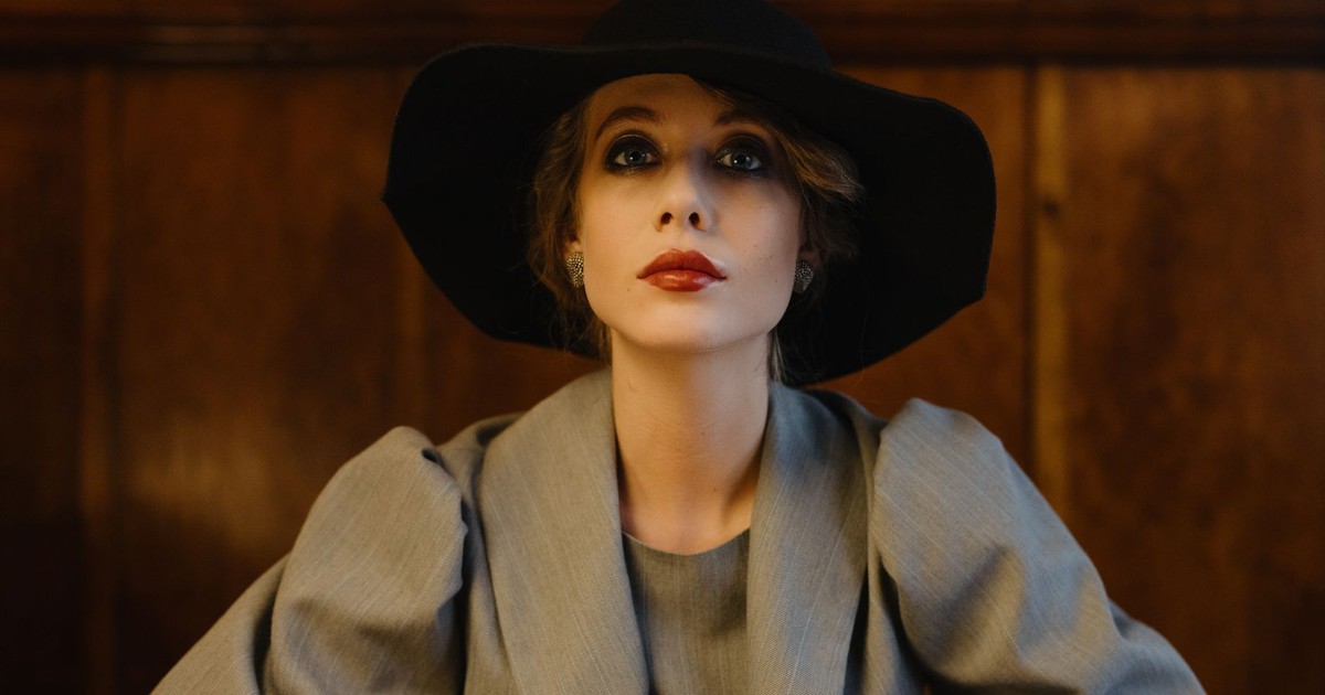 Portrait of an elegant woman in vintage attire with a wide-brimmed hat and red lips.