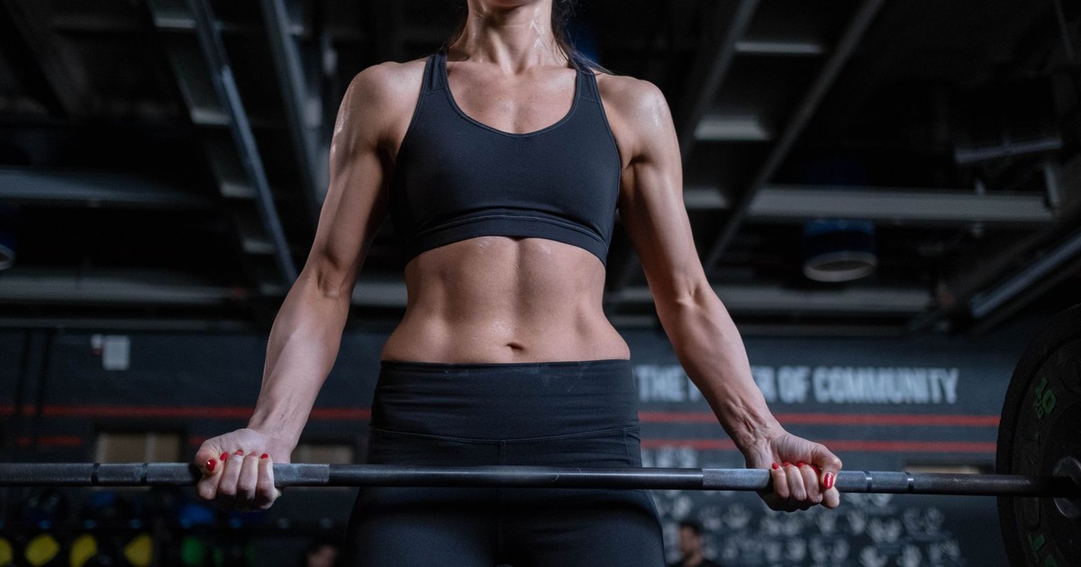 Strong woman lifting barbell in gym. Focus on fitness, strength, and healthy living.