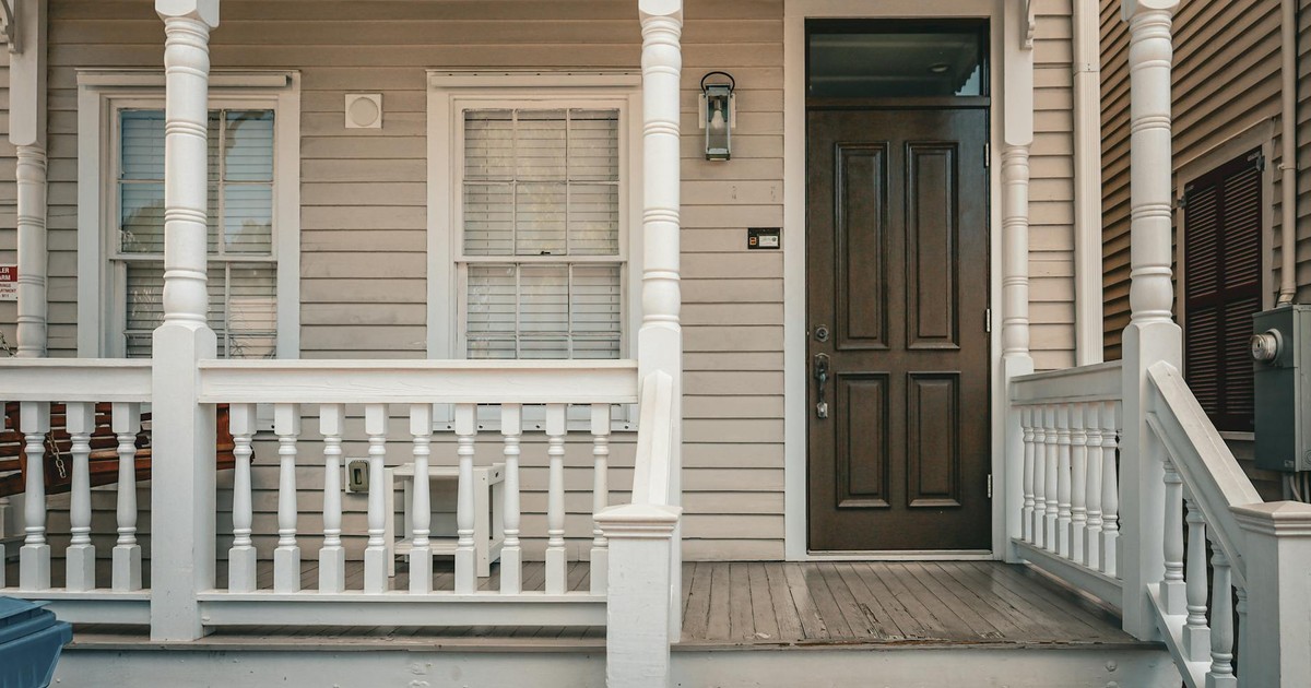 A classic wooden house porch with a decorative entrance and picket fence.