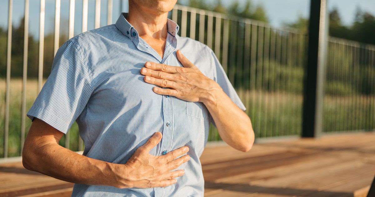 A man practicing relaxation with hands on chest and abdomen outdoors.