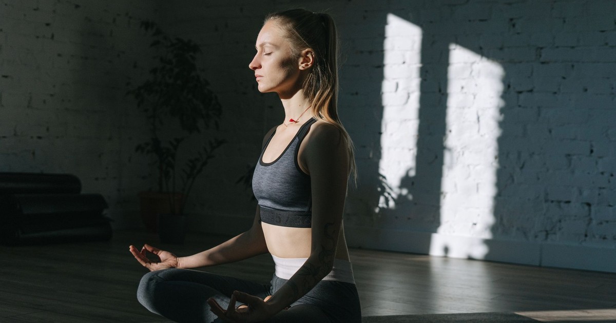 Woman in lotus position meditating indoors, embracing mindfulness and tranquility.