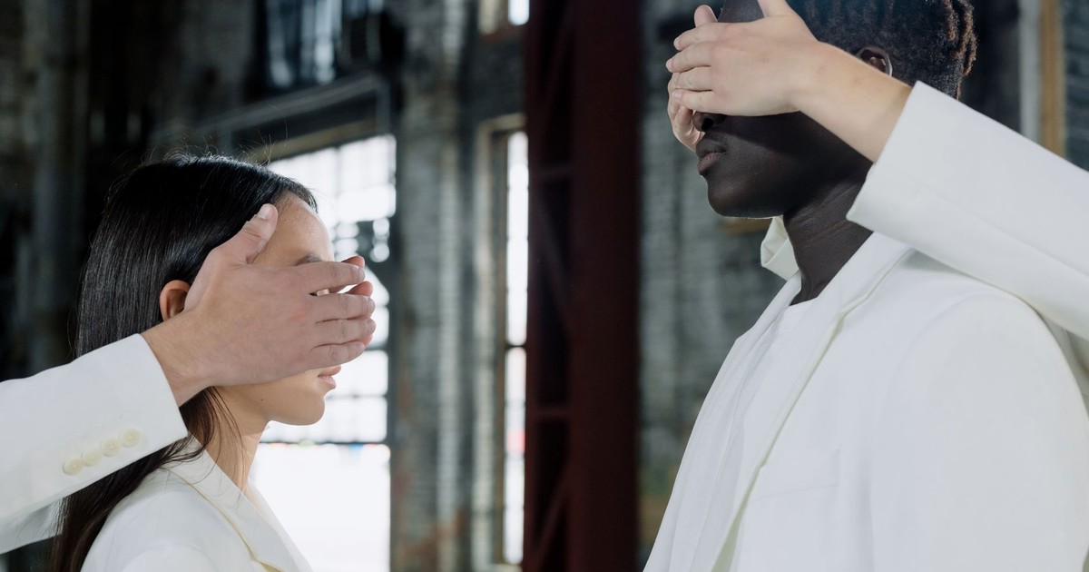 Surreal portrait of diverse people, eyes covered, in industrial setting.
