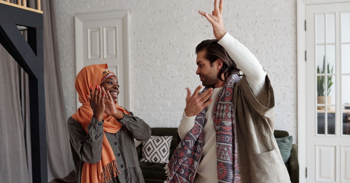 A happy multiracial couple dancing and celebrating together indoors.