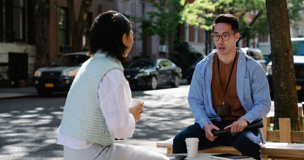 Two colleagues engaged in a conversation outdoors on a sunny day in an urban street.
