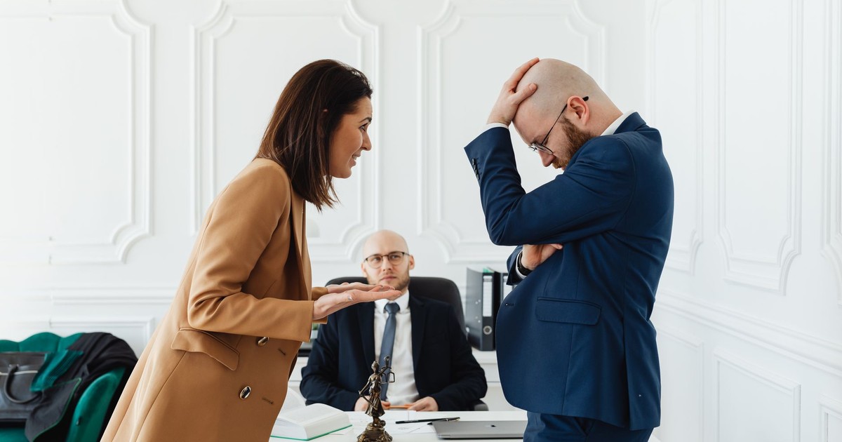 A couple having a heated argument in a law office with their attorney observing.