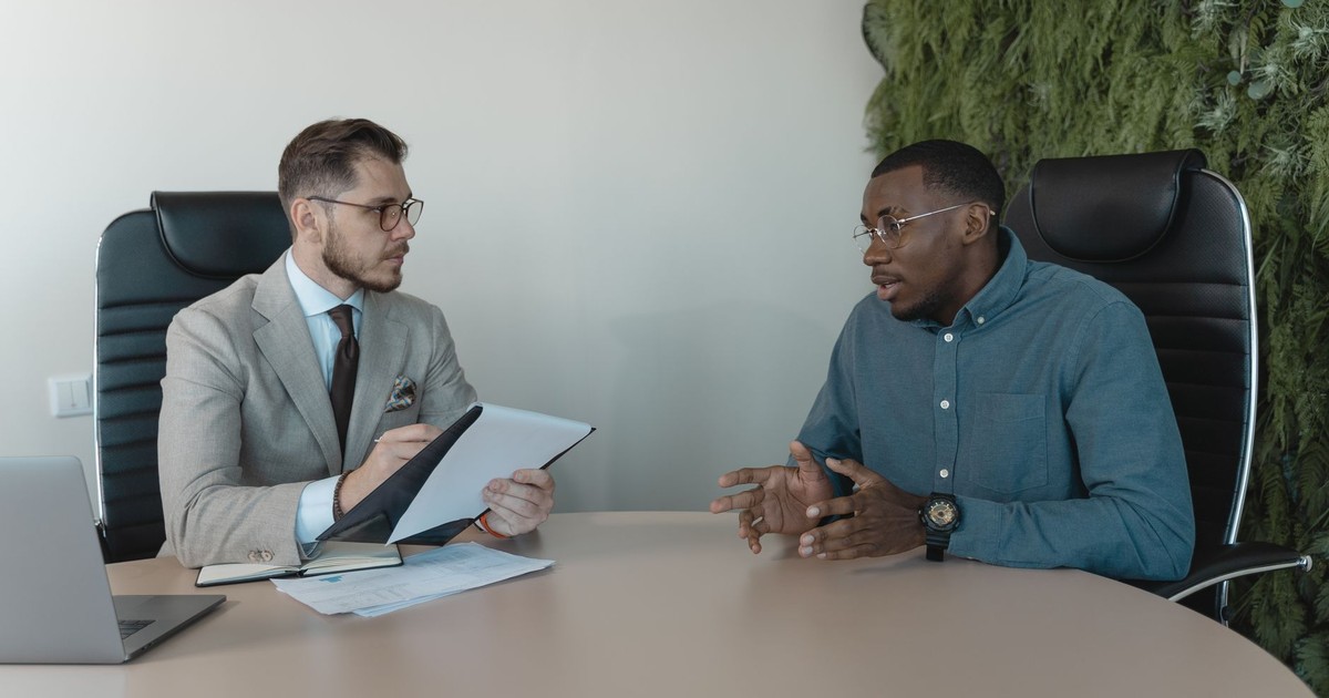Two businessmen engaged in a discussion during a job interview in a contemporary office environment.