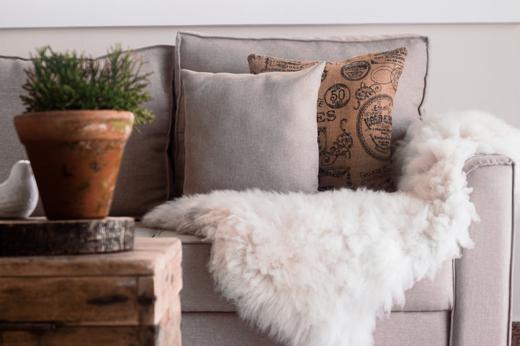 Warm and inviting living room with a focus on soft textures, featuring a sofa with fur throws and decorative pillows