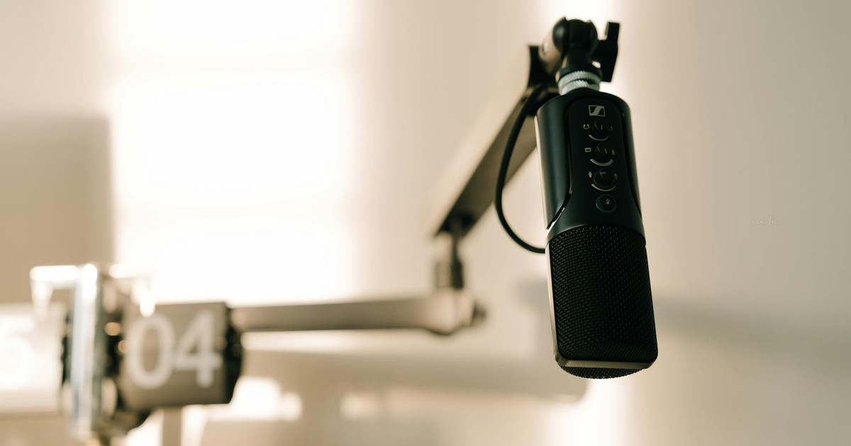 A sleek professional microphone on a boom arm in a minimalist studio.