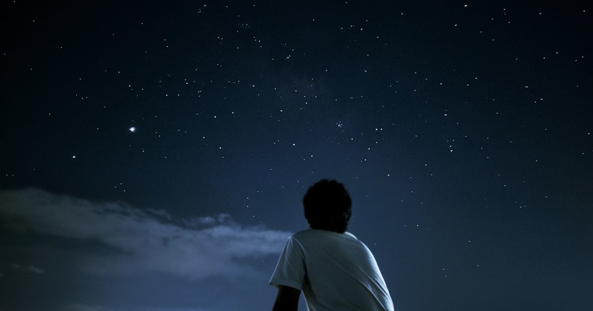 man in white t-shirt standing on field during night time