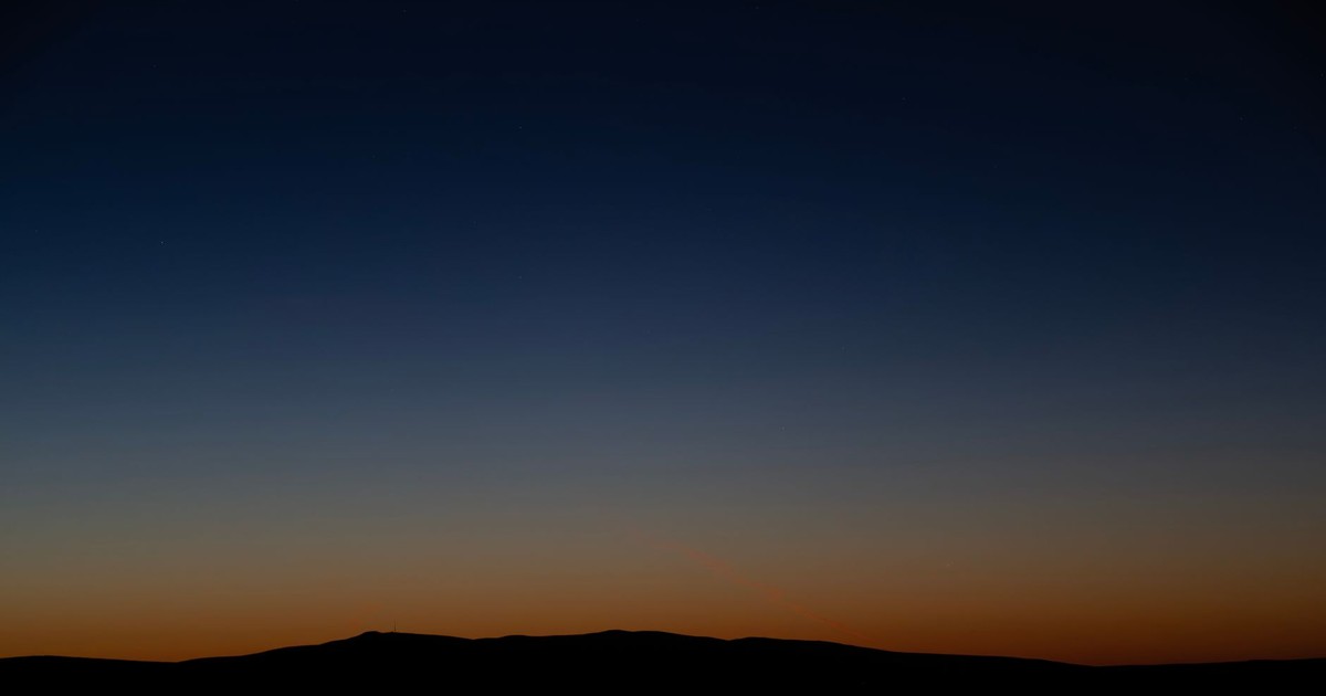 Crescent moon over East Wenatchee skyline at twilight, capturing serene natural beauty.
