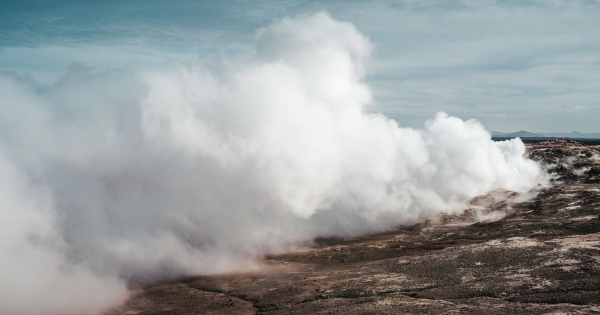 Majestic geothermal steam venting from Icelandic terrain on a clear day.