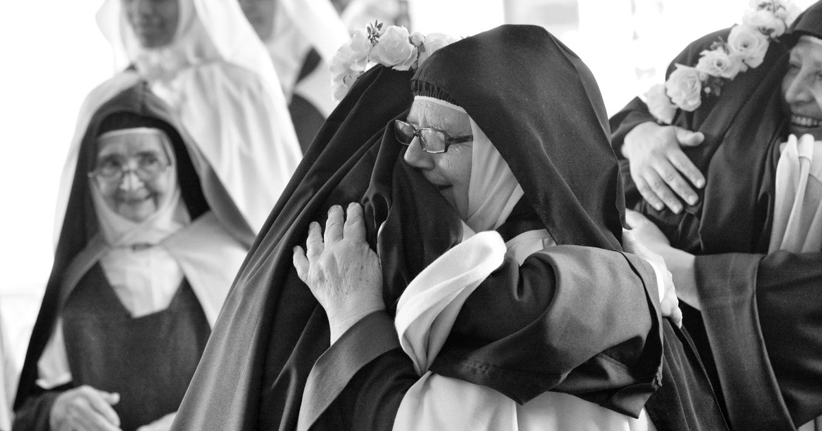 A heartfelt embrace between nuns at a religious celebration, capturing joy and camaraderie.