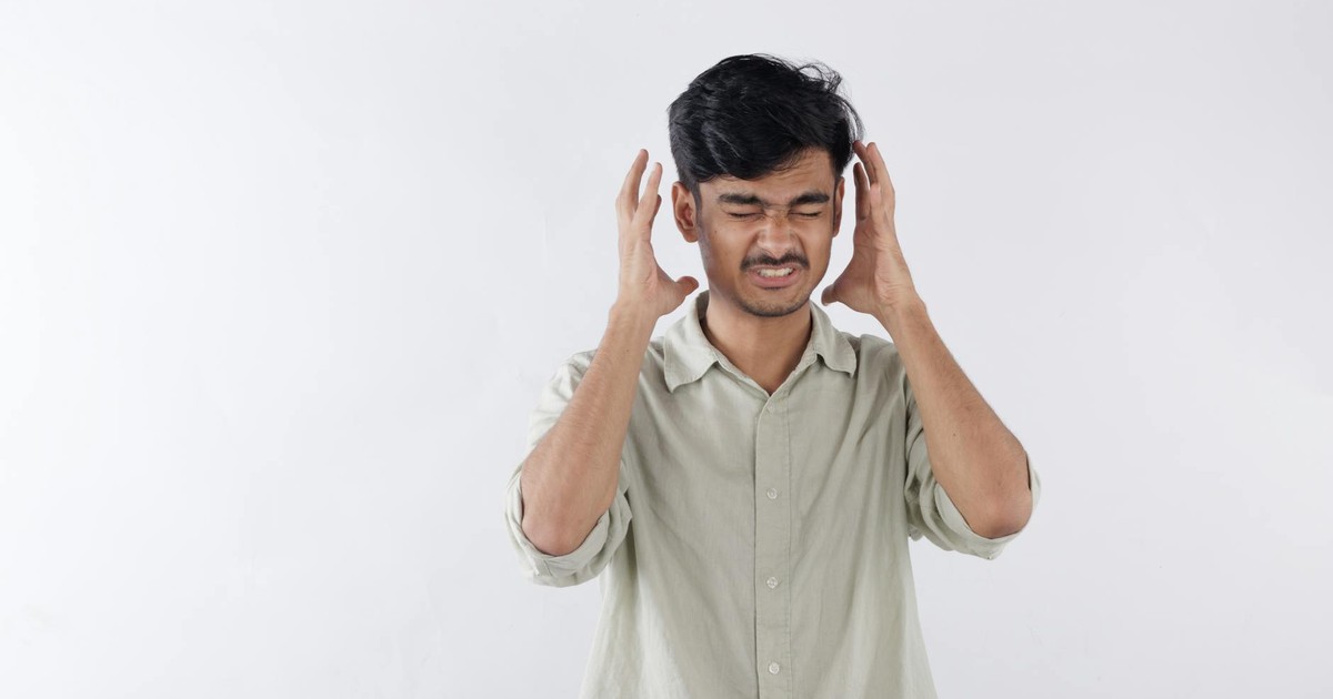 Young man expressing frustration, hands on head, isolated background.