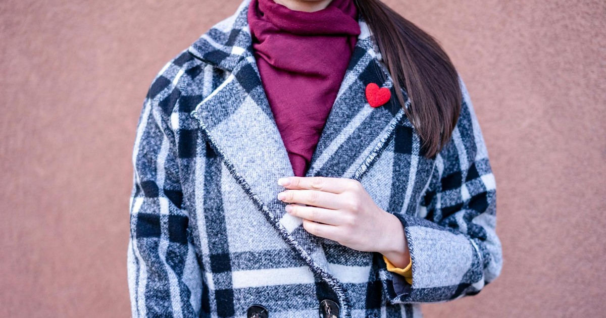 Fashionable woman in a checkered coat with heart brooch, adding elegance and warmth.