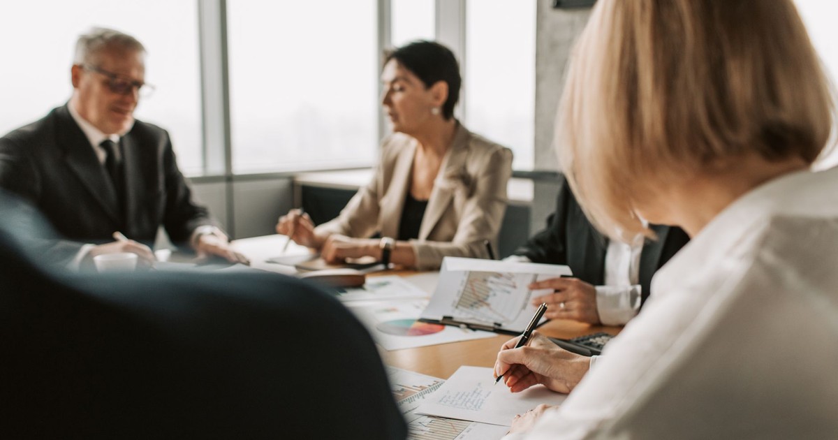 Colleagues discussing documents in a corporate office meeting.
