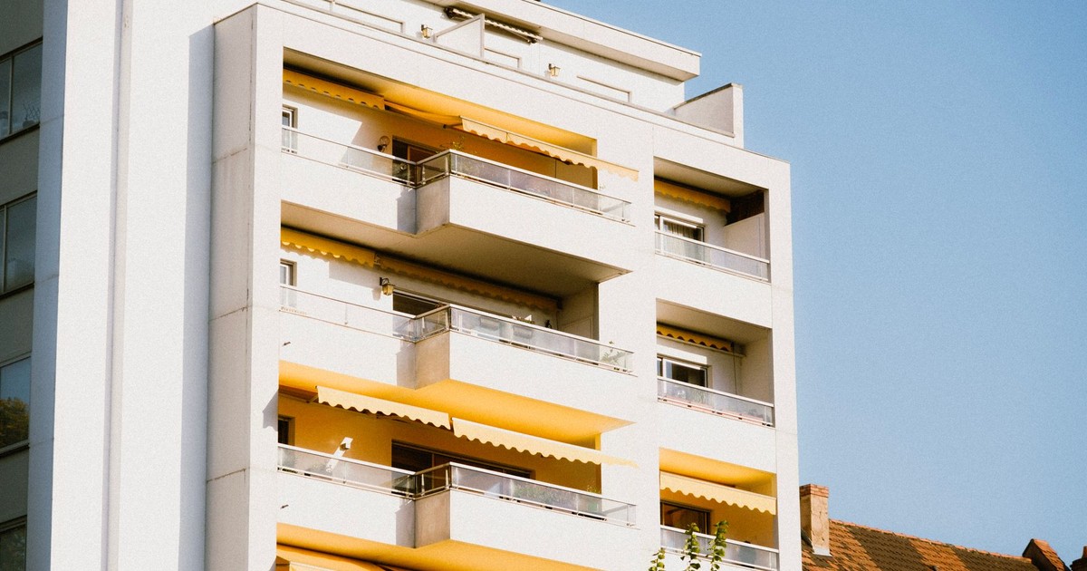 Low-angle view of a contemporary apartment building with yellow balconies against a clear sky.