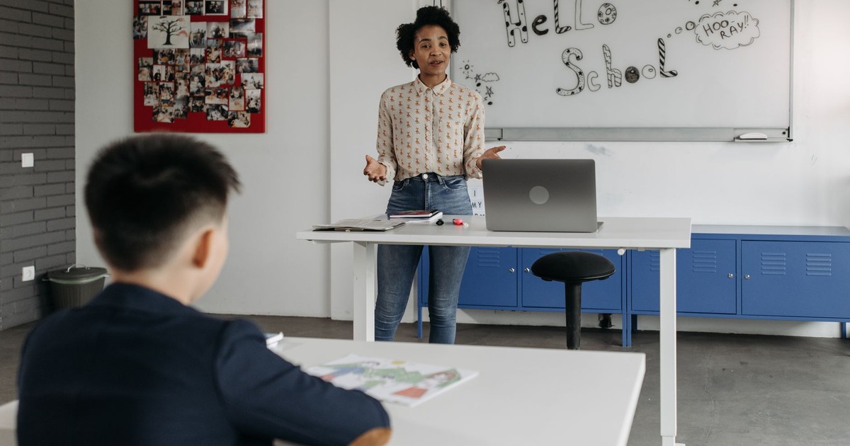 Educator leads interactive lesson in a classroom with a whiteboard display.