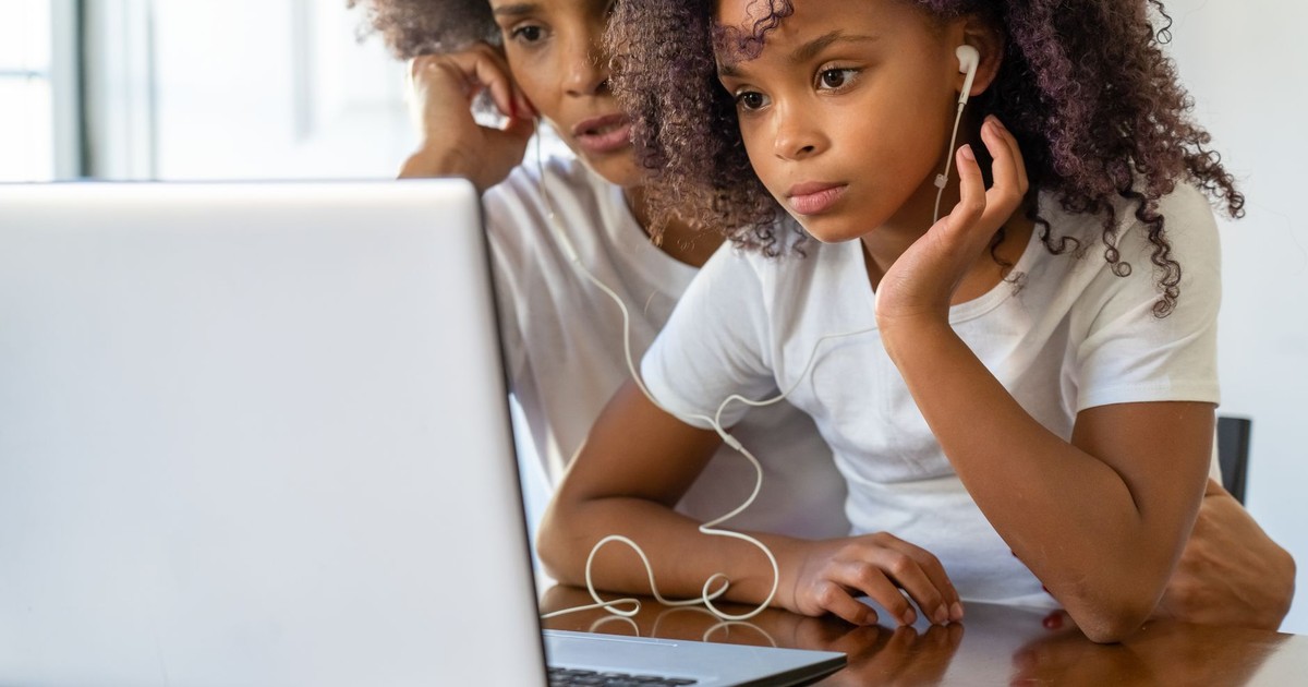 African American mother and daughter using a laptop together indoors, bonding and learning.