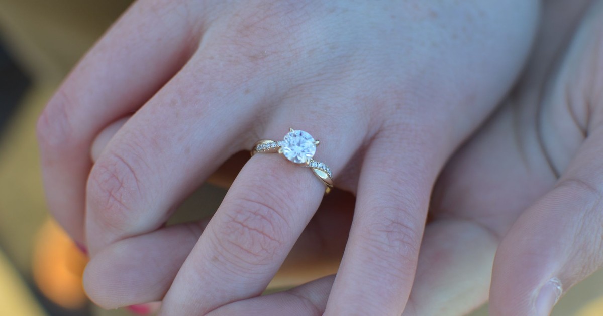 Intimate view of an engagement ring being slipped onto a finger, symbolizing love and commitment.